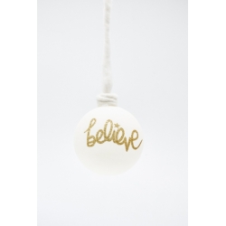 Witte kerstbal met gouden glitters en de tekst "believe", hangend aan een touwtje.