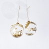 Twee glazen kerstballen met gouden teksten en een strik, gevuld met glitters.