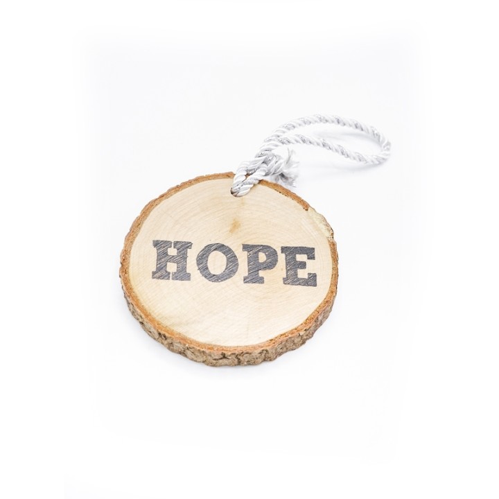 Houten schijf met de tekst "HOPE", omringd door een natuurlijke schorsrand en touw.