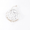 A circular white decoration with intricate star cutouts, packaged with twine.