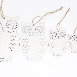 Four white wooden owl decorations with intricate cutouts and twine hangers.