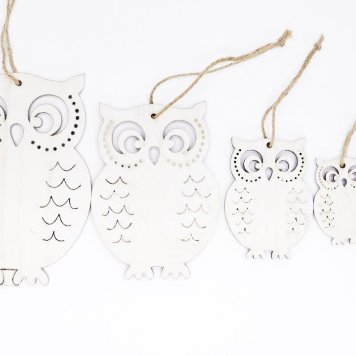 Vijf witte uilvormige decoraties met schattige details, opgehangen met touw.
