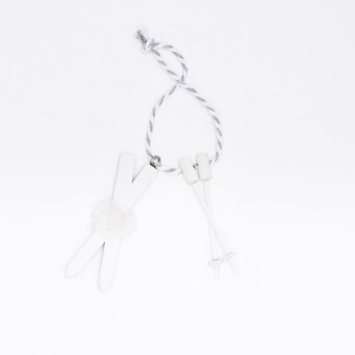 Witte knijper met een pluizig accessoire, bevestigd aan een touwtje met kleine witte stekkers.