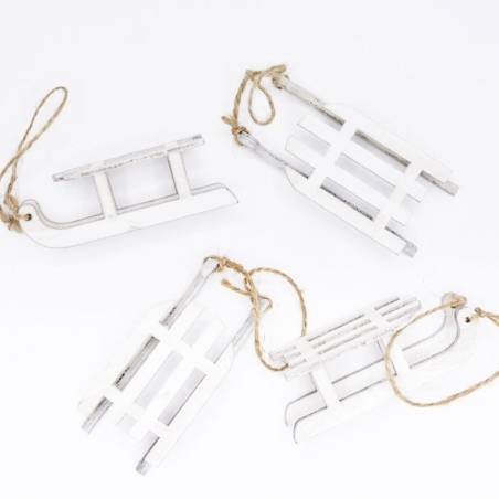 Four small white wooden sleds with twine for hanging, arranged playfully on a white background.