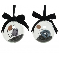 Two glass ornaments with abstract face designs, featuring black and earthy tones and velvet bows.