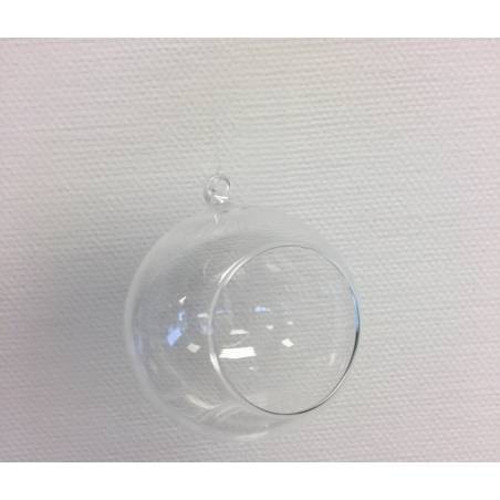 A clear glass orb with a small opening, suspended against a textured white background.