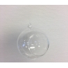 A clear glass orb with a small opening, suspended against a textured white background.