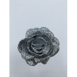 Glanzende, zilveren rozenknop bedekt met glitters op een lichte achtergrond.