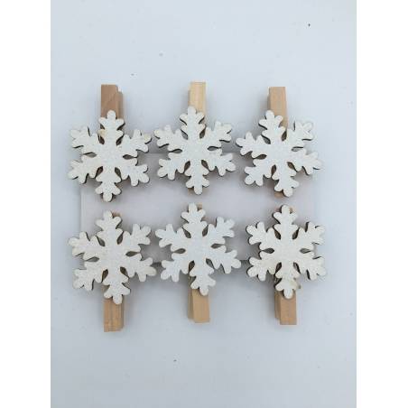 Wooden clothespins adorned with white, snowflake-shaped decorations.