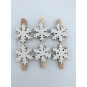 Wooden clothespins adorned with white, snowflake-shaped decorations.