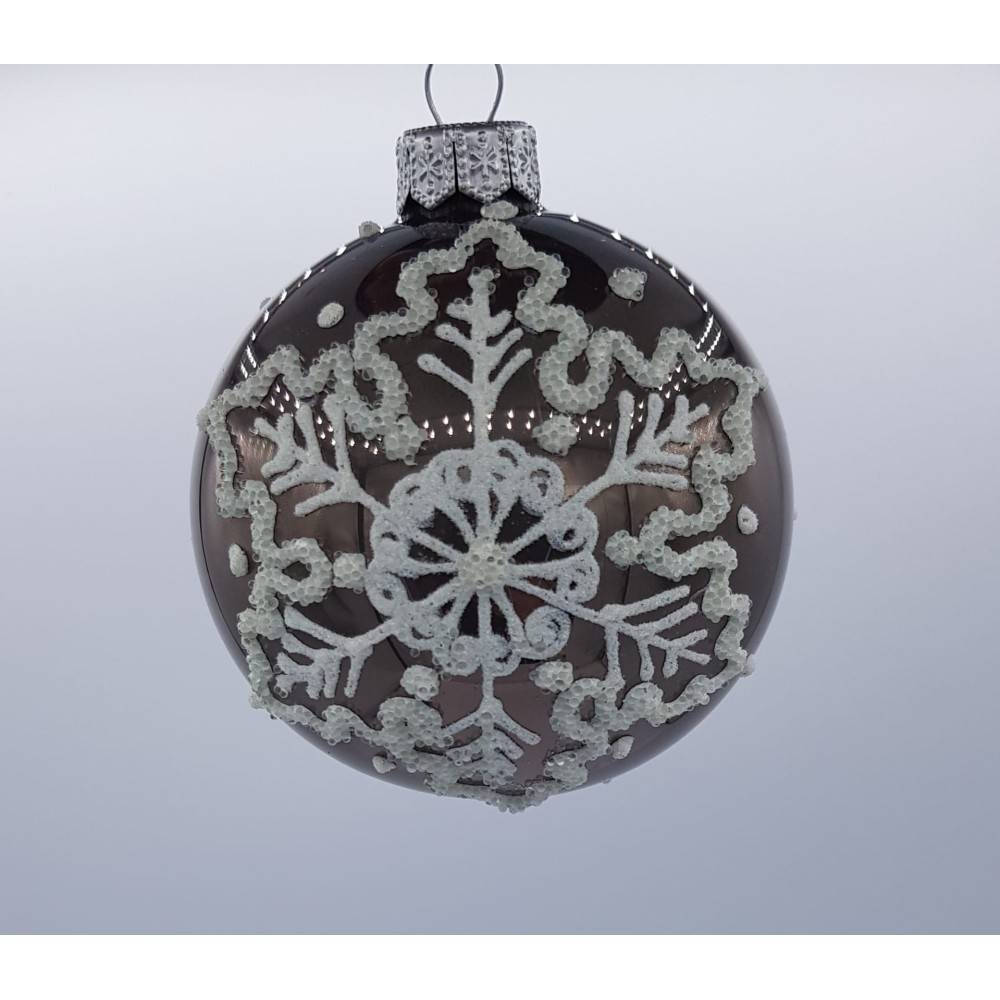 A dark glass ornament adorned with intricate white snowflake designs and silver accents.