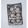 Six round, brown ornaments with white snowflake designs, nestled in a gray box.