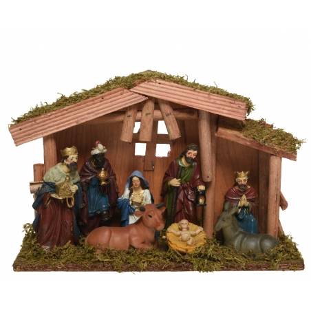 A rustic nativity scene with figures, animals, and a thatched roof, surrounded by moss.