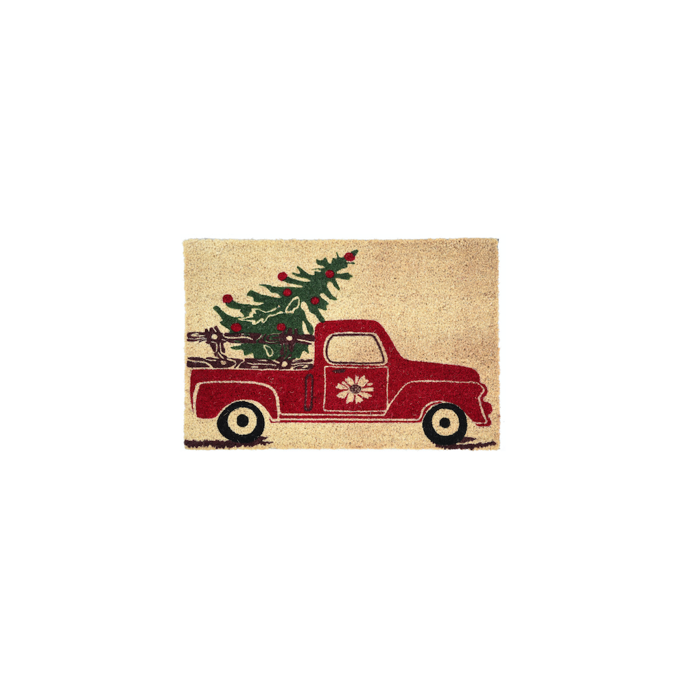 A festive red truck carrying a Christmas tree on a sandy beige doormat.