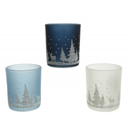 Three frosted glass candle holders in blue, navy, and white, adorned with snowy forest scenes.