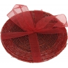 A round woven basket in warm red tones, elegantly tied with a sheer red ribbon.