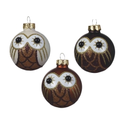 Three decorative owl-themed Christmas ornaments in white, brown, and black with glitter accents.