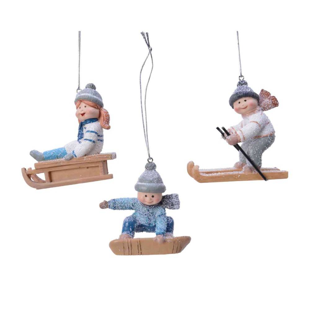 Three whimsical figurines of children enjoying winter sports, adorned with soft colors and sparkles.