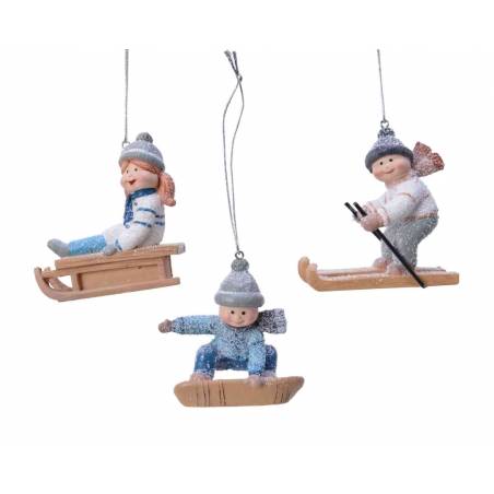 Three whimsical figurines of children enjoying winter sports, adorned with soft colors and sparkles.