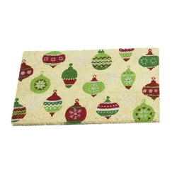 A yellow mat adorned with colorful, festive Christmas ornaments in red and green.
