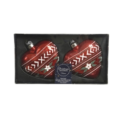 Two red heart-shaped Christmas ornaments with white patterns and floral accents in a box.