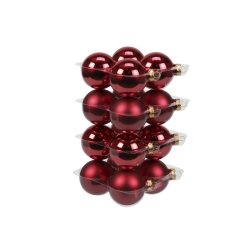 Shiny red Christmas ornaments stacked neatly in a clear container.