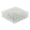 A pile of shiny, iridescent plastic pearls on a clear surface, reflecting light beautifully.