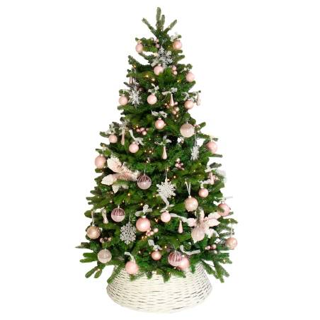 Een groene kerstboom versierd met roze ballen, sneeuwvlokken en een witte mand als standaard.