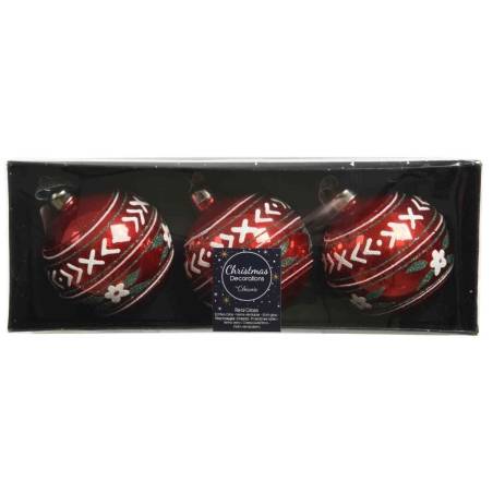 Three shiny red Christmas ornaments with intricate white and green designs in a black box. Three shiny red Christmas ornaments with intricate white and green designs in a black box.
