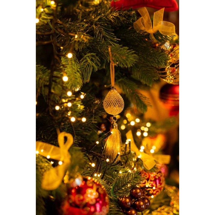Gouden ornamenten en strikken versieren een groene kerstboom, omringd door warme lichtjes.