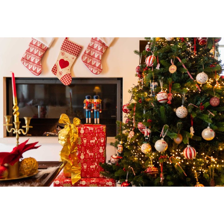 Kerstboom met versieringen, cadeaus en een haard, sfeervol aangekleed met rood en groen.