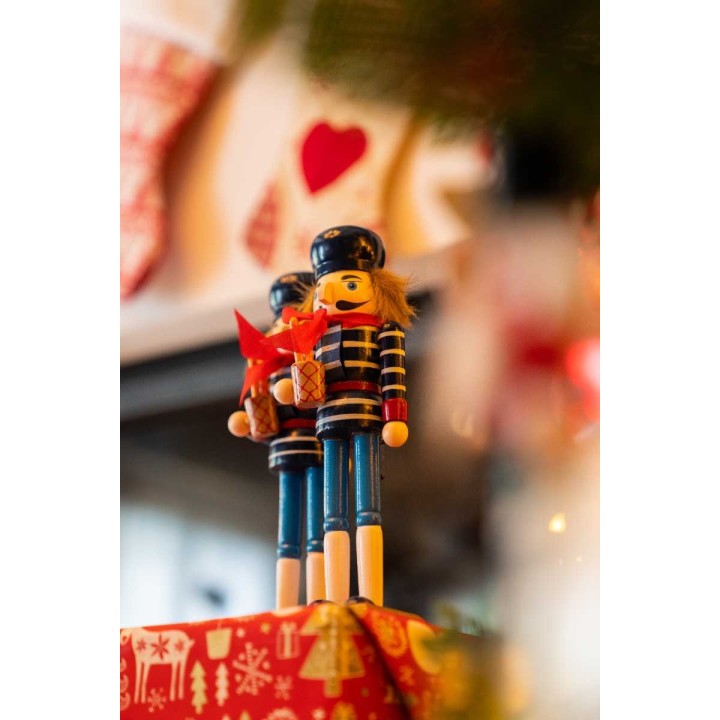 Kleurrijke houten notenkrakers met een feestelijke uitstraling, versierd met bladeren en cadeau.