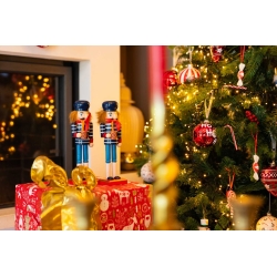 Twee houthakkers in feestelijke kleuren staan naast een kerstboom met glinsterende decoraties.