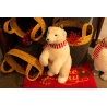 A fluffy white polar bear figurine with a red scarf beside decorative baskets on a festive mat.