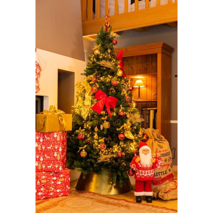 Een versierde kerstboom met gouden decoraties, cadeaus en een kerstman bij een warme woonkamer.