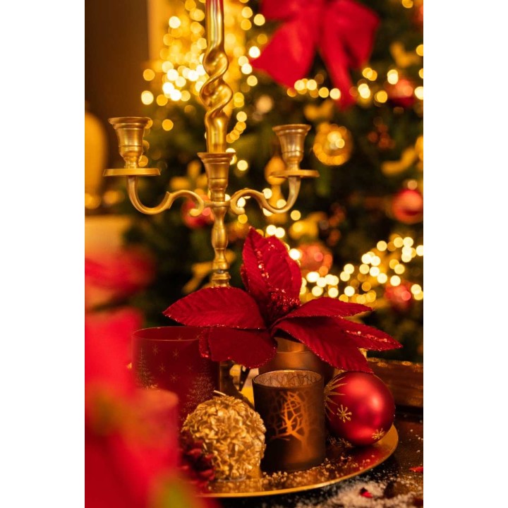 Warme gloed van kaarsen, rode bloemen en kerstversieringen op een feestelijke tafel.