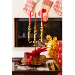 A festive centerpiece with gold candle holders, red candles, and decorative ornaments.