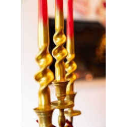 Three elegant, twisted gold candlesticks with bright red candles atop.