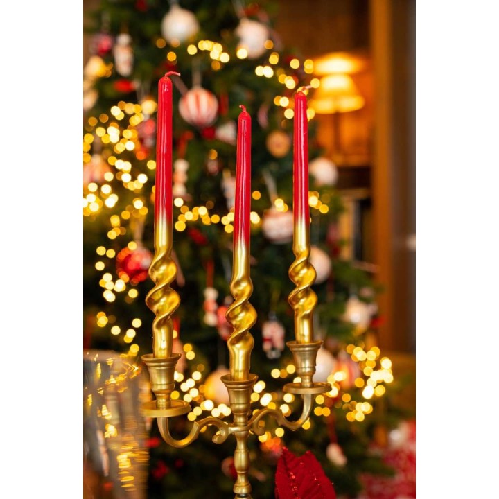 Gouden kandelaar met rode kaarsen, voor een sfeervolle kerstboom vol lichtjes en versieringen.