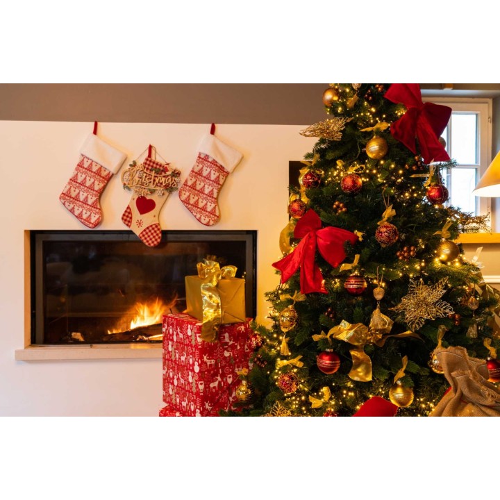 Kerstboom met gouden en rode versieringen, cadeaus en een open haard met sokken eraan.