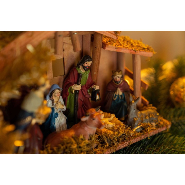 Kleurrijke kerststal met figuren van Maria, Jozef, kindje Jezus en dieren, omringd door hooi.
