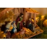 A warm nativity scene with figurines, straw, and soft golden light illuminating the scene.