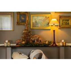 Kerstdecoratie met gouden accenten, een dennenboom en een sfeervolle lamp op een houten tafel.