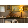 A cozy holiday scene with a golden tree, nativity, and warm lamp on a decorated table.