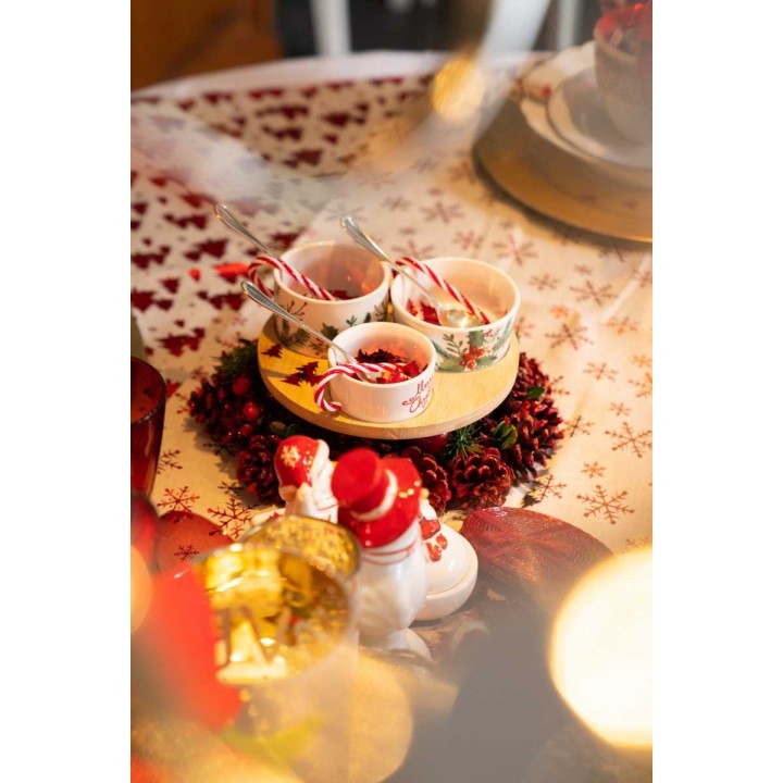 Een sfeervolle tafel met kerstdecoraties, schalen en suikerstokjes op een gebloemde tafelkleed.