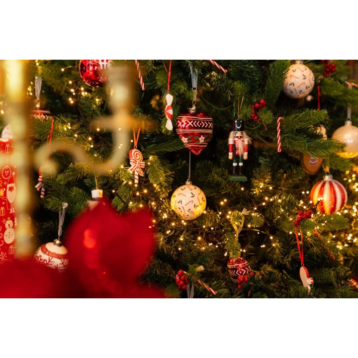 Kerstboom vol kleurrijke ballen, snoepjes en lichtjes, met een warme, feestelijke uitstraling.