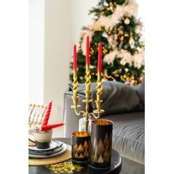 Elegante kaarsenhouder met rode kaarsen, naast een kerstboom en sfeervolle decoraties.