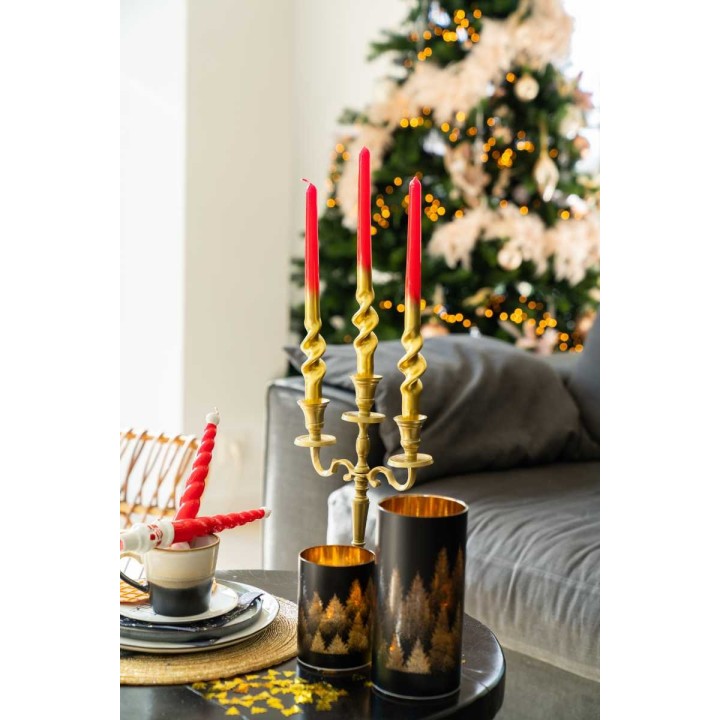 Elegante kaarsenhouder met rode kaarsen, naast een kerstboom en sfeervolle decoraties.