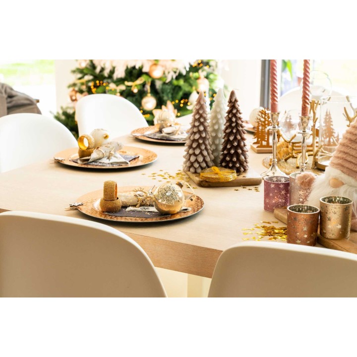 Feestelijke tafel met gouden accenten, kerstdecoraties en smalle dennenbomen.