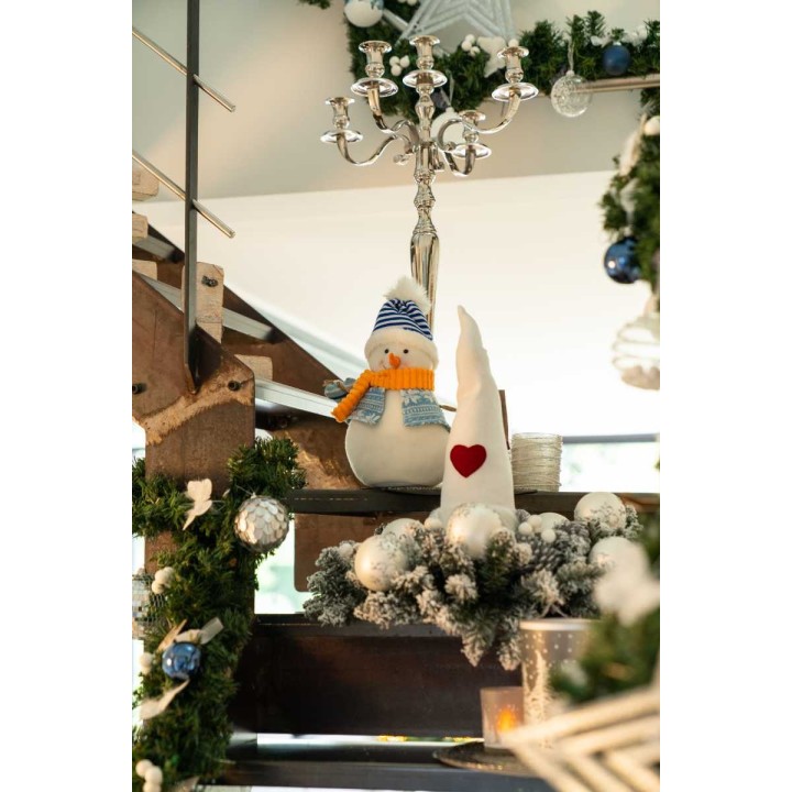 Sfeervolle kerstdecoratie met een sneeuwman, een witte kerstboom en glinsterende ornamenten.
